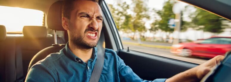 An angry looking man driving a car